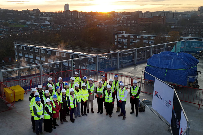 Guests in hi vis jackets on top of the new Greenwich Campus with the sun going down in the background