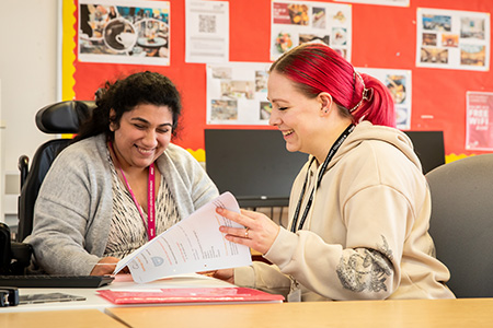 Tutor and student laughing at a desk